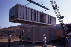 A manufactured home being constructed on site using a crane.
