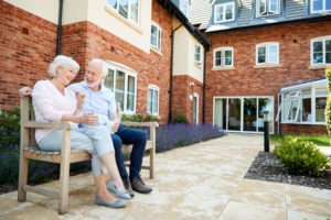 Image of elderly couple sitting on a bench laughing