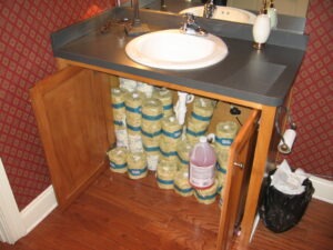 Under-sink storage area filled with bathroom supplies.