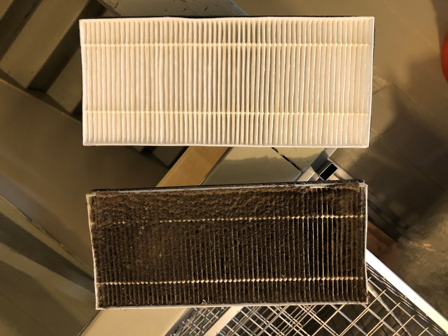 Comparison of a clean ERV filter and a heavily darkened filter clogged with smoke and particulate matter during a wildfire event.
