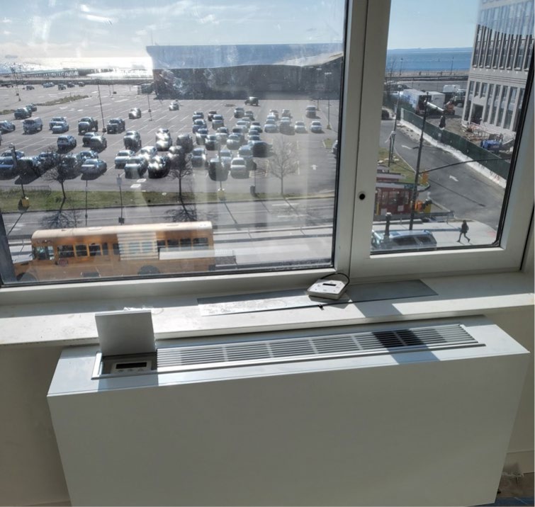 Cold-climate packaged terminal heat pump installed under a window in apartment.
