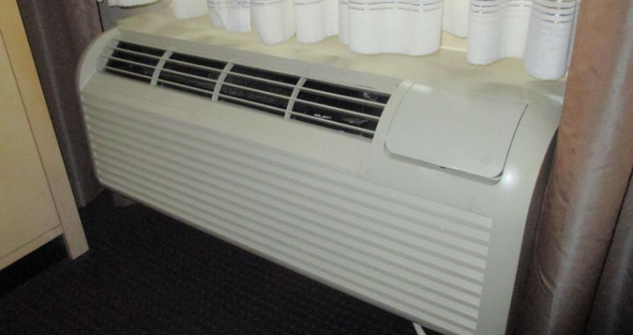 Conventional packaged terminal air conditioner installed beneath a hotel room window.