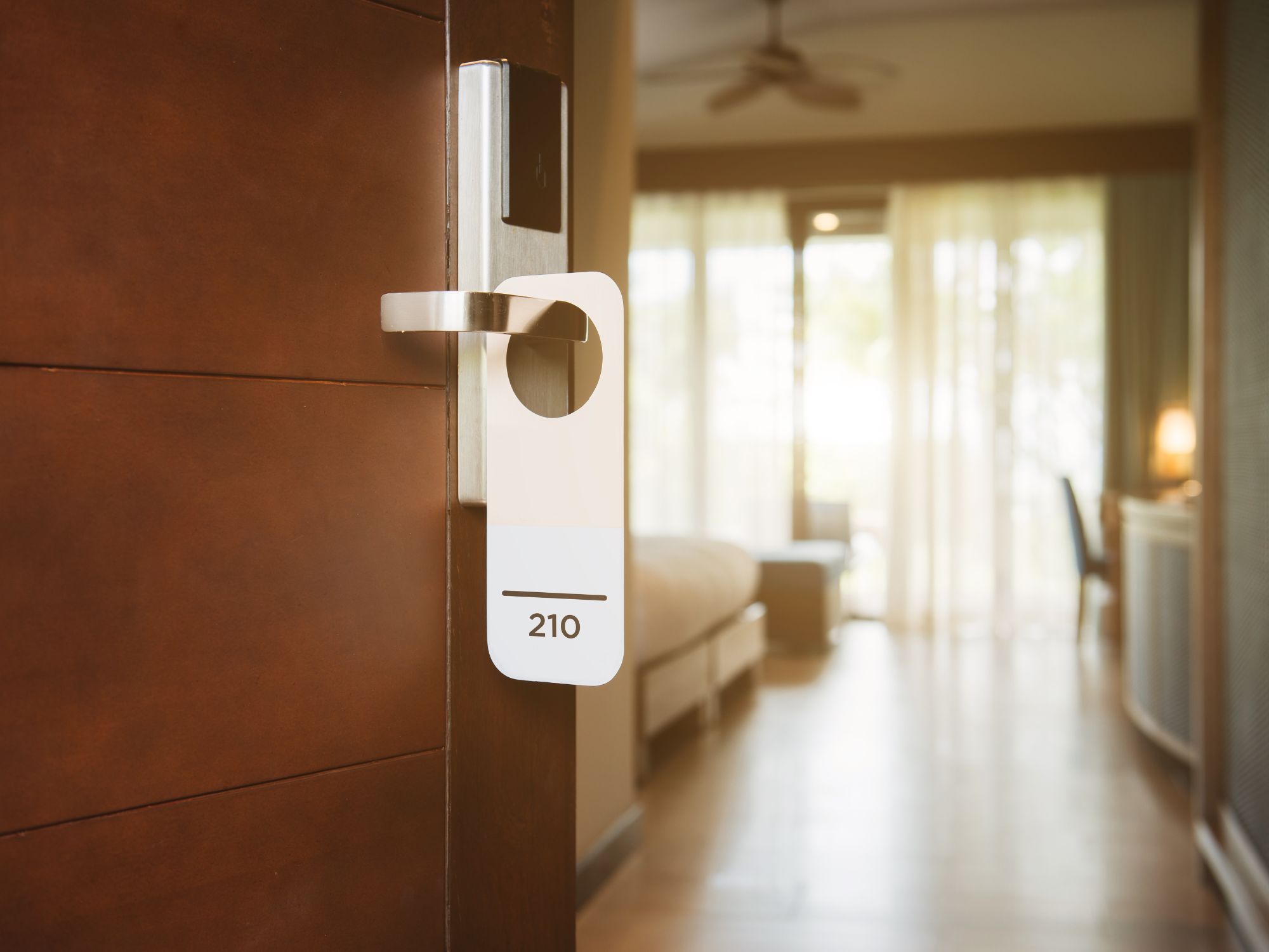 Open hotel guest room door showing an accessible room entrance and sleeping area beyond.
