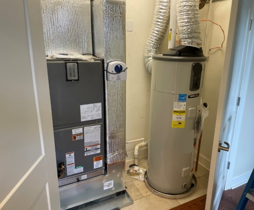 Integrated heat pump water heater installed in an enclosed mechanical closet with ducted connections and adjacent HVAC equipment