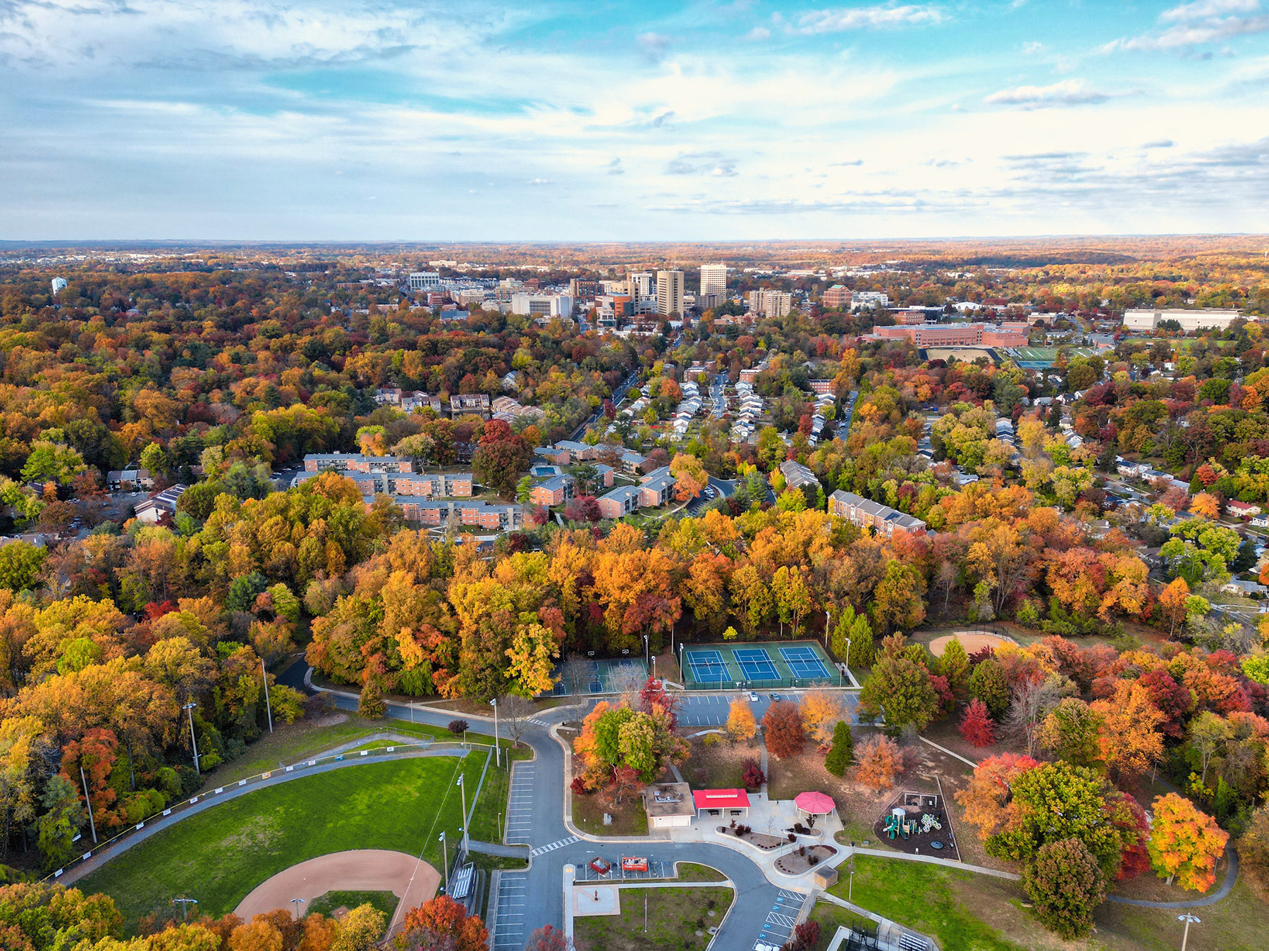 Aerial view of the suburban Rockville, Maryland community with apartment buildings, parks, and tree‑lined streets surrounded by fall foliage.