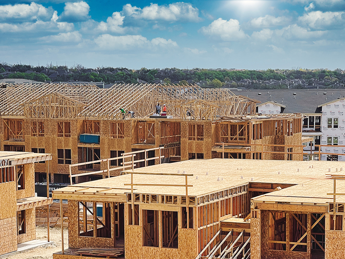 Wood‑framed multifamily residential buildings under construction at a large development site.