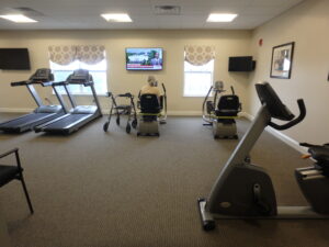 A room with fitness equipment spaced out with clearance space at each machine.