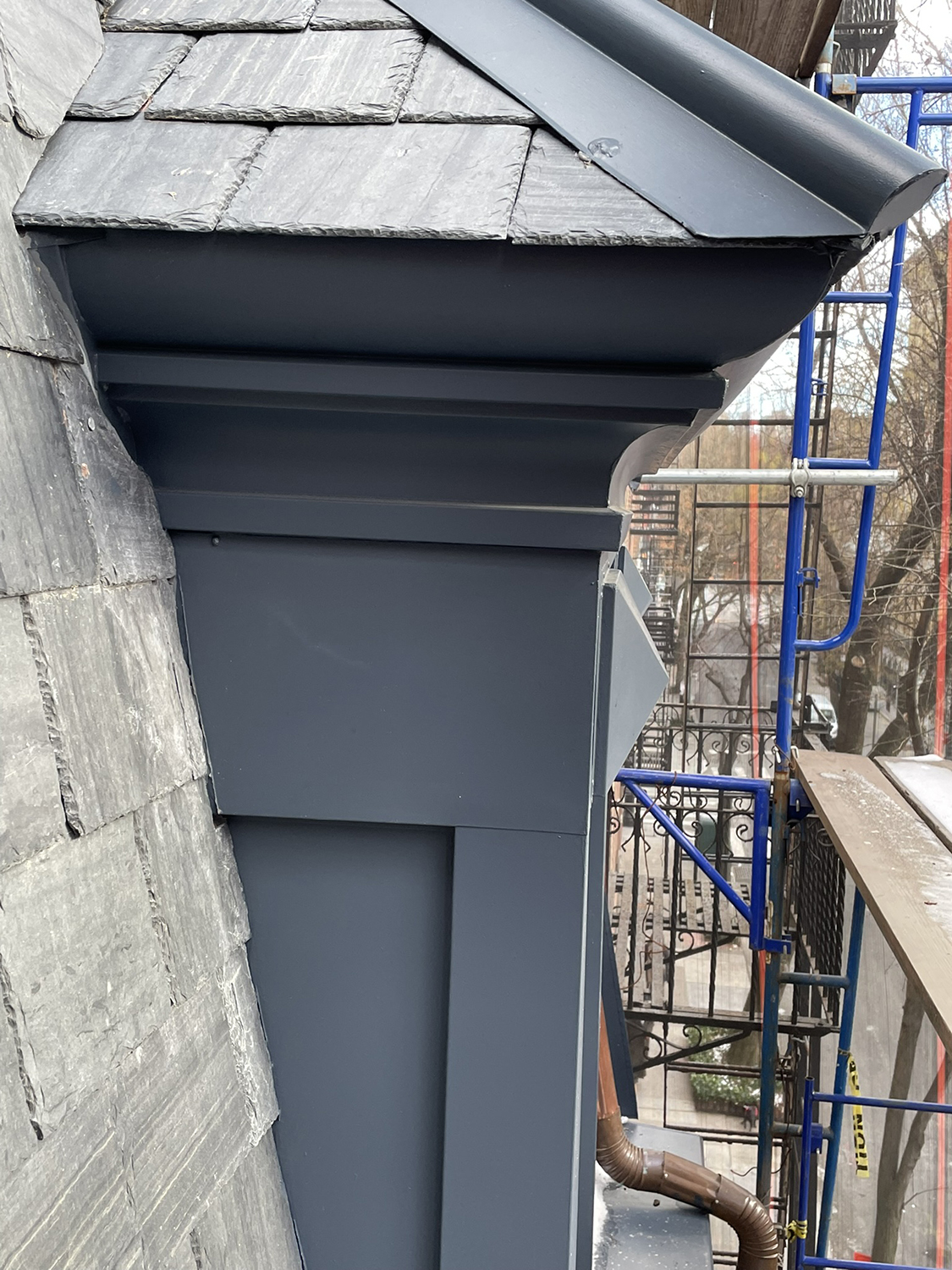 Restored mansard roof detail with new slate cladding and metal flashing on the Twin Sisters townhouses, shown during construction.