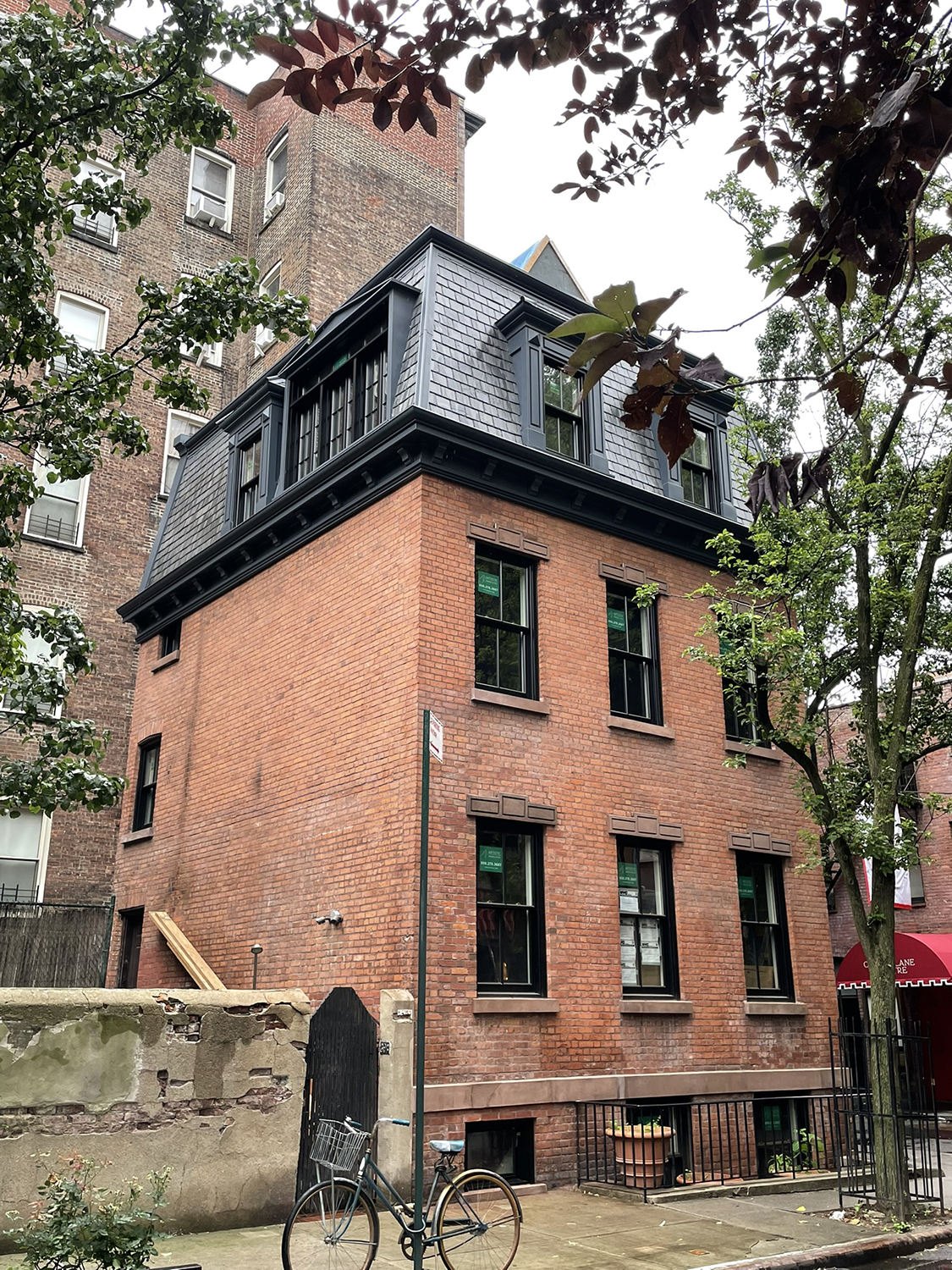 Completed restoration of a Twin Sisters townhouse, showing rebuilt mansard roof, restored brick façade, and landmark residential setting.