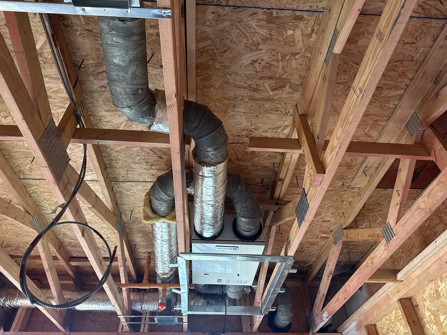 Ventilation unit and insulated ductwork installed within the exposed framing of an apartment.
